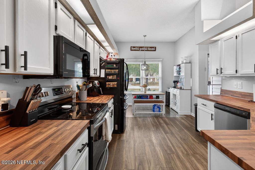 86093 Santa Barbara Street Yulee, FL 32097 - Photo 22 of 51 a kitchen with stainless steel appliances granite countertop a stove top oven a sink dishwasher and cabinets with wooden floor