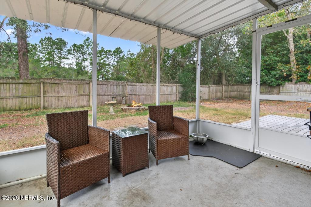 86093 Santa Barbara Street Yulee, FL 32097 - Photo 45 of 51 a view of a patio with couches chairs under an umbrella with a small yard
