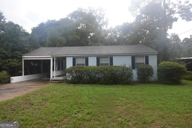 a view of a house next to a yard with plants and trees