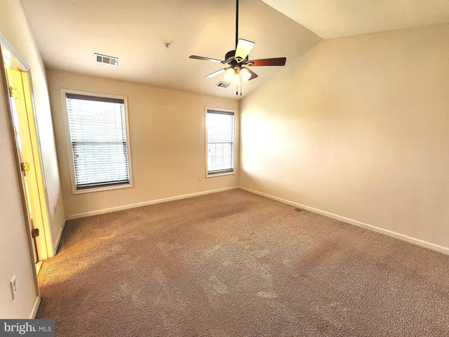 an empty room with windows and chandelier fan