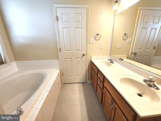 a spacious bathroom with a tub sink and mirror