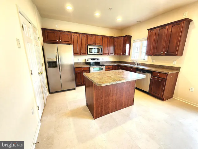 a kitchen with stainless steel appliances granite countertop a refrigerator a sink and a stove