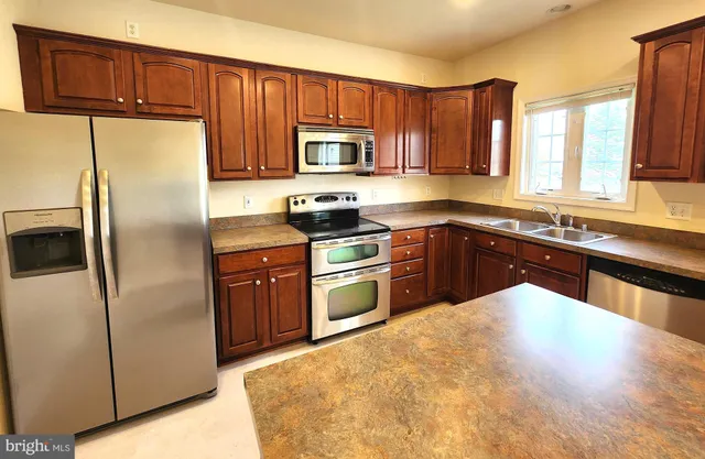 a kitchen with stainless steel appliances granite countertop a stove a sink dishwasher a refrigerator and cabinets with wooden floor