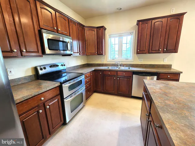 a kitchen with stainless steel appliances granite countertop wooden cabinets a stove top oven a sink and dishwasher