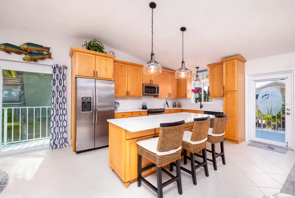 a open kitchen with stainless steel appliances granite countertop a stove top oven a sink a dining table and chairs with the floor