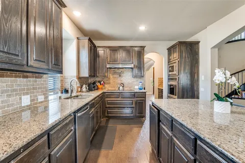 a kitchen with granite countertop a sink stainless steel appliances and cabinets