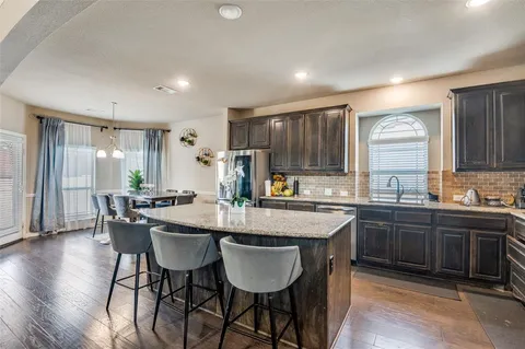a kitchen with granite countertop a dining table chairs and white cabinets
