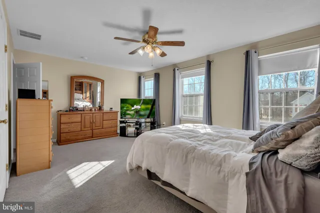 a spacious bedroom with a bed a window and a flat screen television