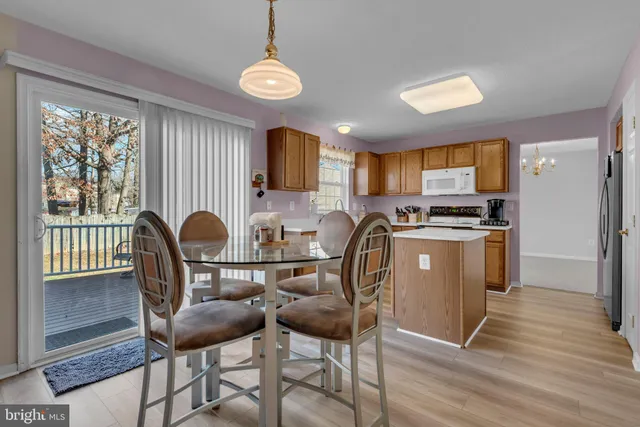 a kitchen with granite countertop a stove a sink dishwasher a dining table and chair with wooden floor