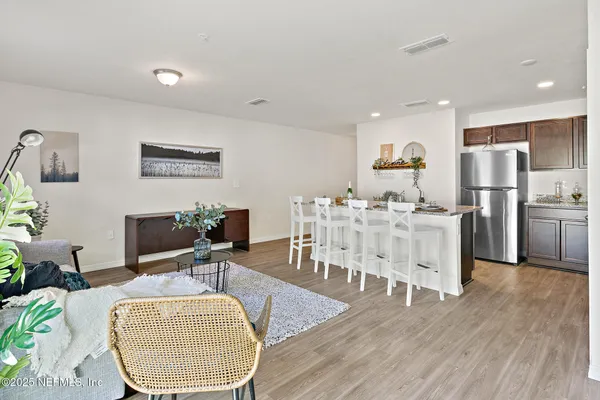 a living room with furniture a wooden floor and kitchen view