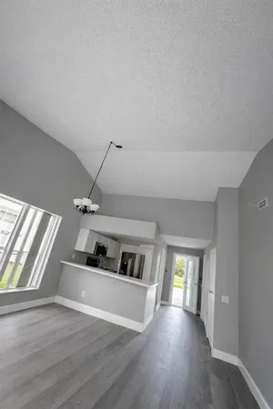 a view of a livingroom with wooden floor and a kitchen space