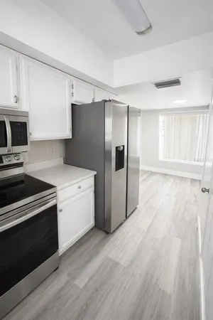 a kitchen with granite countertop a refrigerator and a stove top oven
