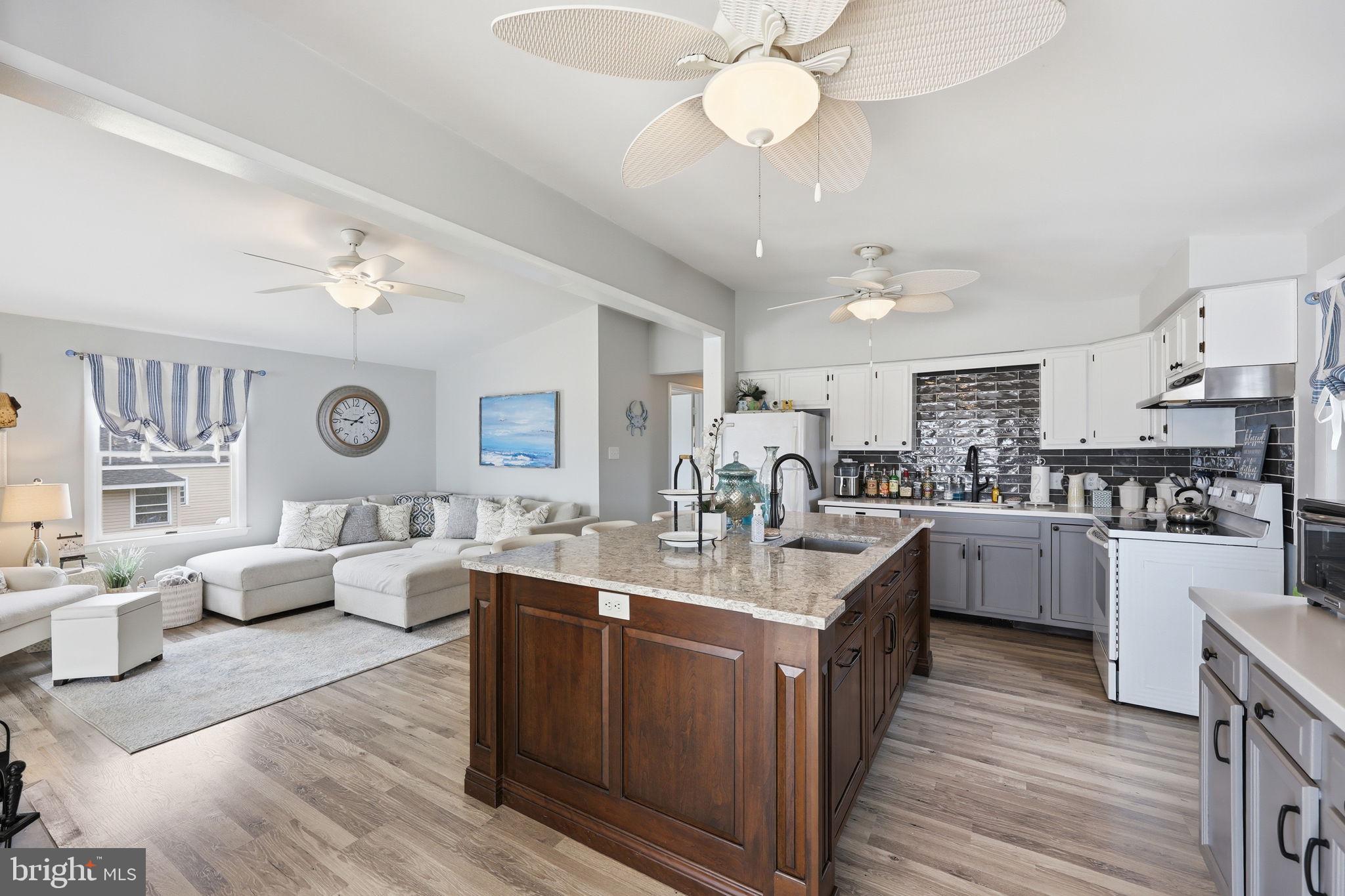 173 Cove Road Newport, NJ 08345 - Photo 8 of 72 a kitchen with a sink dishwasher a stove top oven a dining table and chairs with wooden floor