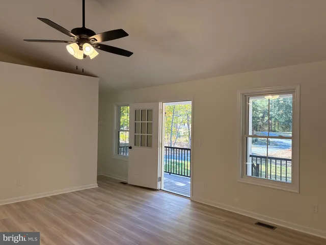 a view of an empty room with window and wooden floor