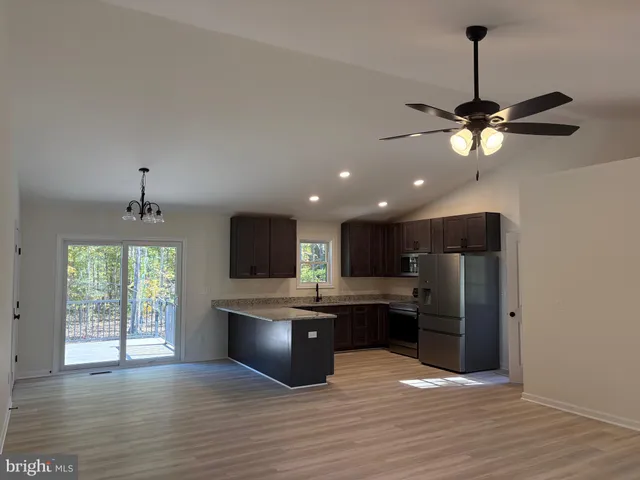 a large kitchen with stainless steel appliances granite countertop a refrigerator a stove a sink dishwasher and a microwave oven on the wooden floor