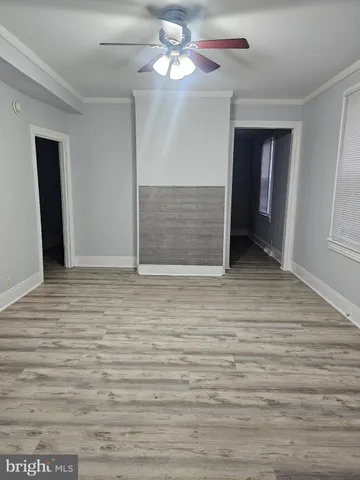 a view of an empty room with window and chandelier fan