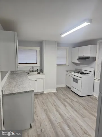 a kitchen with stainless steel appliances white cabinets and a wooden floor