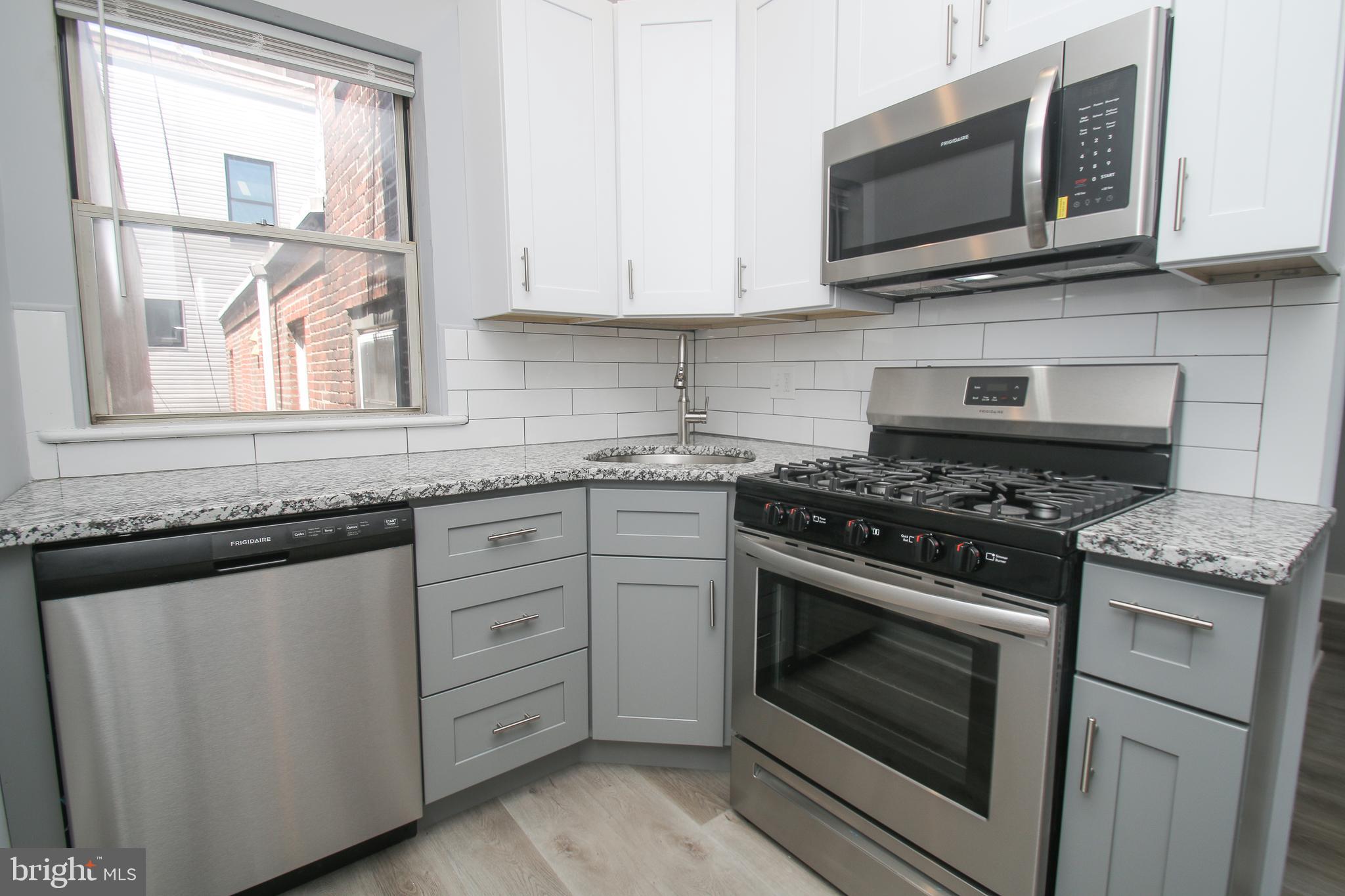 a kitchen with stainless steel appliances granite countertop white cabinets granite counter tops and a window