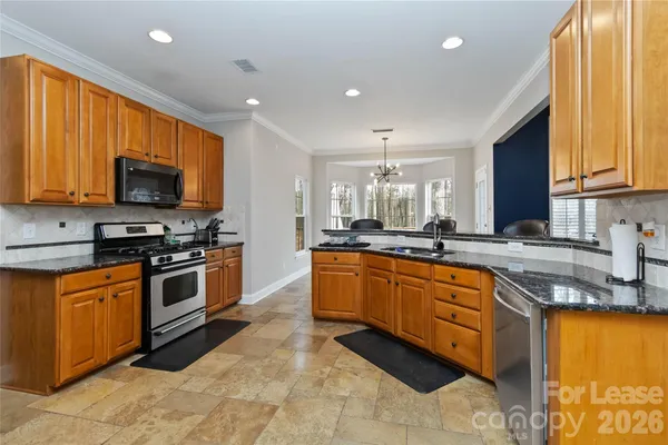 a large kitchen with stainless steel appliances granite countertop a stove a sink and a microwave