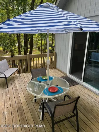 a roof deck with a dining table and chairs with wooden floor