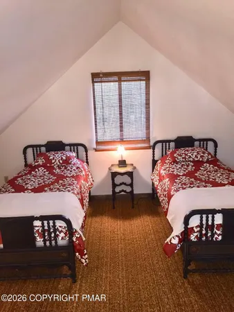 a bedroom with a bed next to a window with chair and dresser