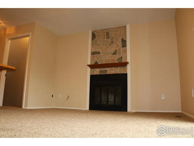 a view of an empty room with wooden floor and a fireplace