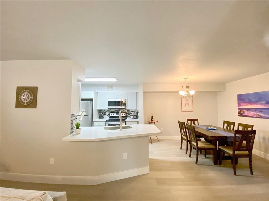 3207 Clint Moore Road, Unit 104 Boca Raton, FL 33496 - Photo 2 of 46 a dining room with kitchen island furniture a chandelier and kitchen view