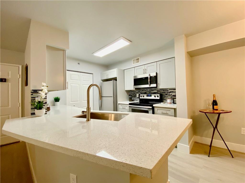 3207 Clint Moore Road, Unit 104 Boca Raton, FL 33496 - Photo 6 of 46 a kitchen with kitchen island a counter top space appliances and cabinets