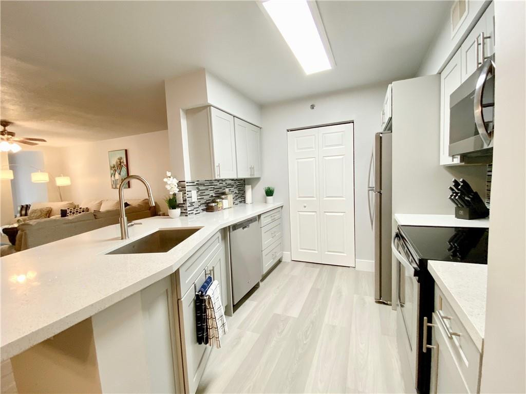 3207 Clint Moore Road, Unit 104 Boca Raton, FL 33496 - Photo 8 of 46 a kitchen with a sink stove top oven and white cabinets