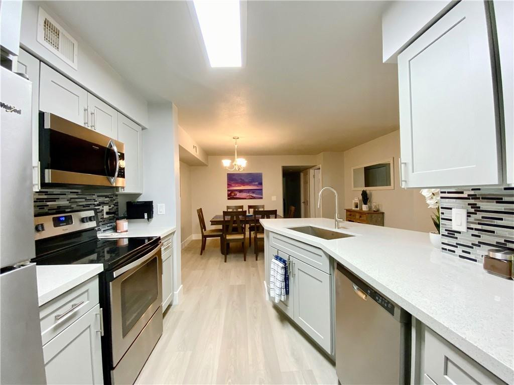 3207 Clint Moore Road, Unit 104 Boca Raton, FL 33496 - Photo 9 of 46 a kitchen with stainless steel appliances a stove sink microwave and cabinets