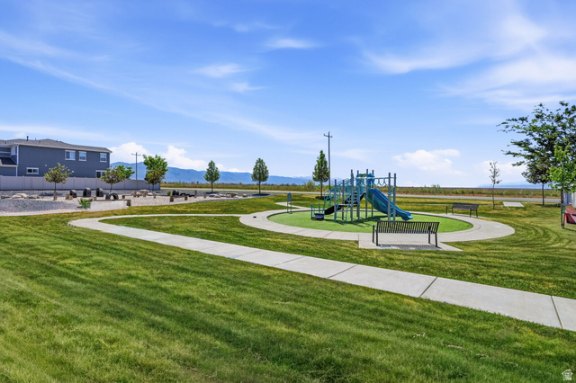1175 Silver Hollow Road Syracuse, UT 84075 - Photo 34 of 34 Community playground area featuring a blue and green play structure, a surrounding artificial turf surface, and multiple benches