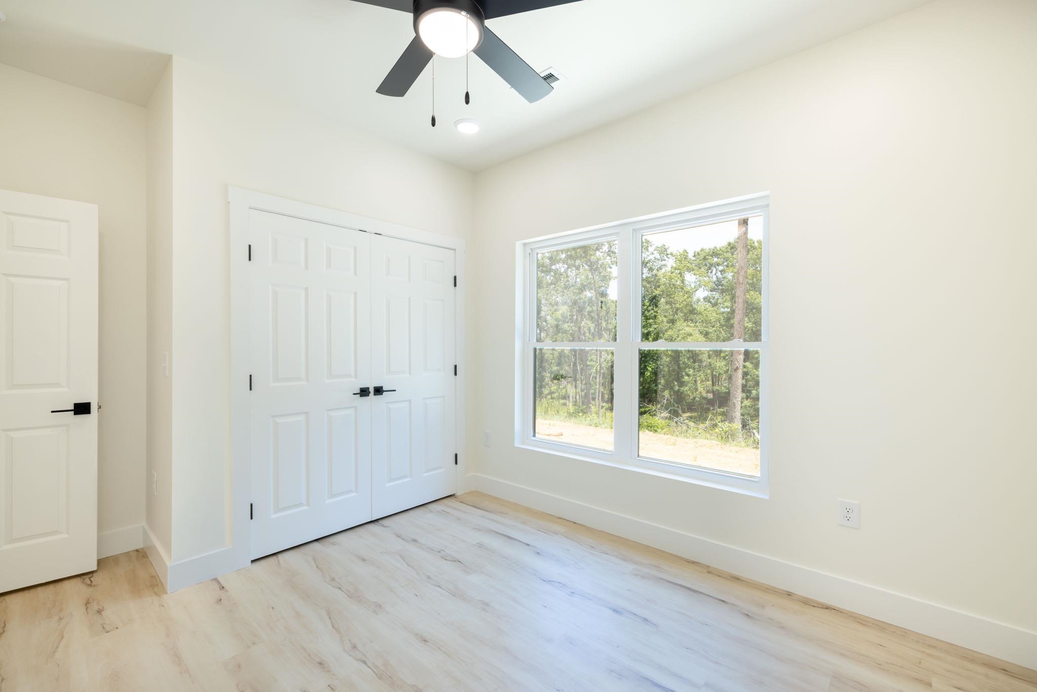 37 William Teague Lane Ramer, TN 38367 - Photo 37 of 39 Bedroom featuring a large window, light wood-finish flooring, a ceiling fan with integrated lighting, and a closet with double panel doors