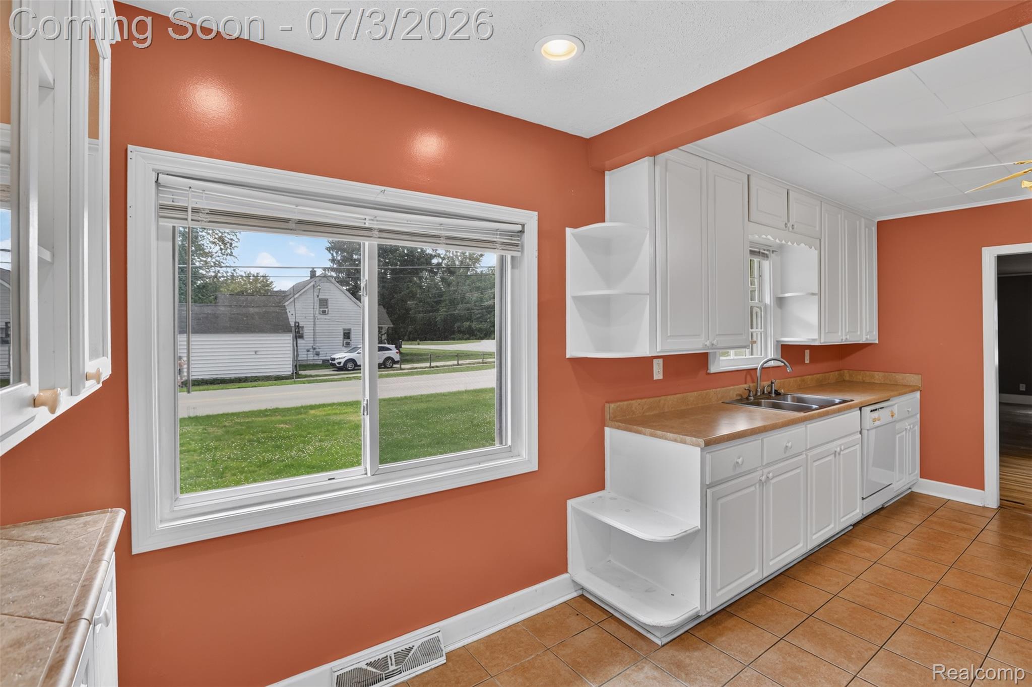 4322 Baker Road Bridgeport, MI 48722 - Photo 6 of 29 Kitchen featuring white cabinetry, tan countertops, a stainless steel sink with a dual-handle faucet, a dishwasher, and tan tile flooring