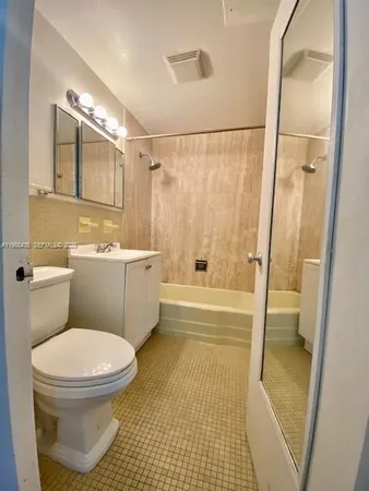 a bathroom with a toilet a sink a mirror a bathtub and shower
