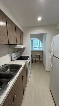 a kitchen with a sink a refrigerator and cabinets
