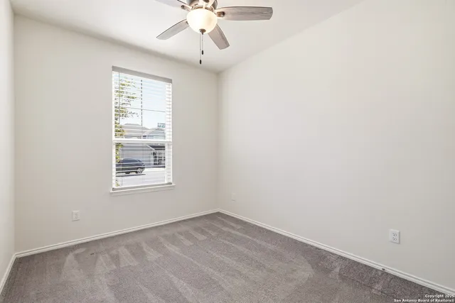 an empty room with a chandelier fan and windows