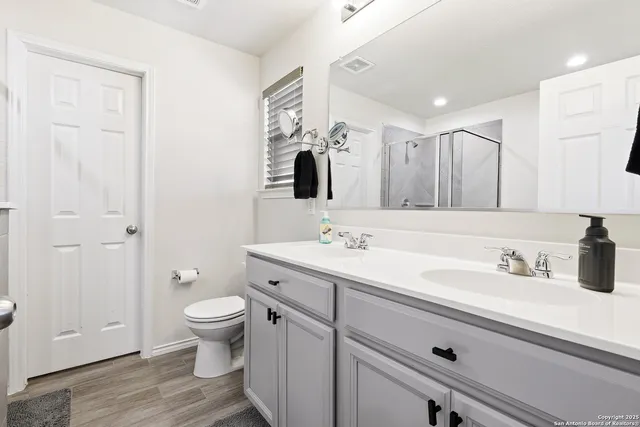 a bathroom with a toilet sink double vanity and mirror
