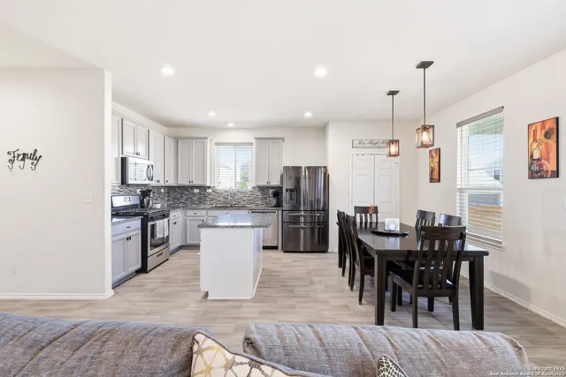 a kitchen with a dining table chairs appliances and cabinets