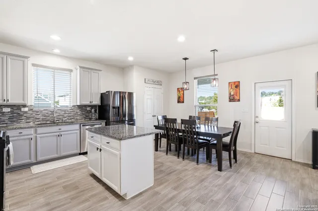a kitchen with stainless steel appliances kitchen island granite countertop a dining table chairs and granite counter tops