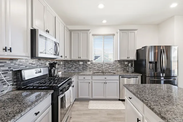 a kitchen with stainless steel appliances granite countertop a sink stove and refrigerator