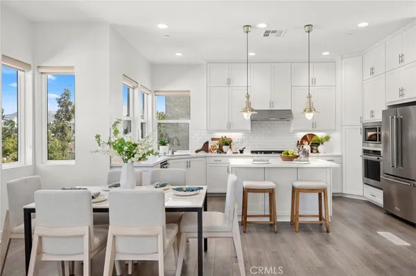 a kitchen with stainless steel appliances granite countertop a table chairs refrigerator and sink