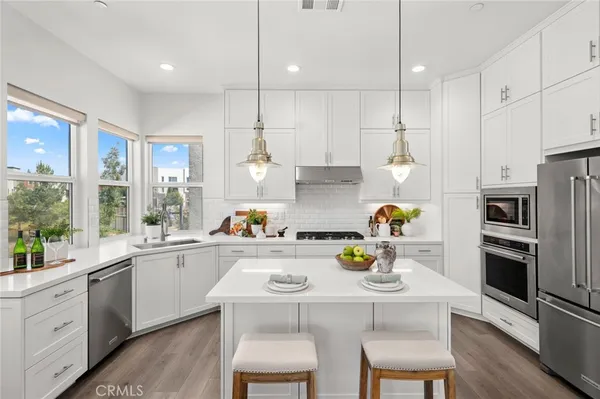 a kitchen with stainless steel appliances a sink a stove a refrigerator cabinets and dining table