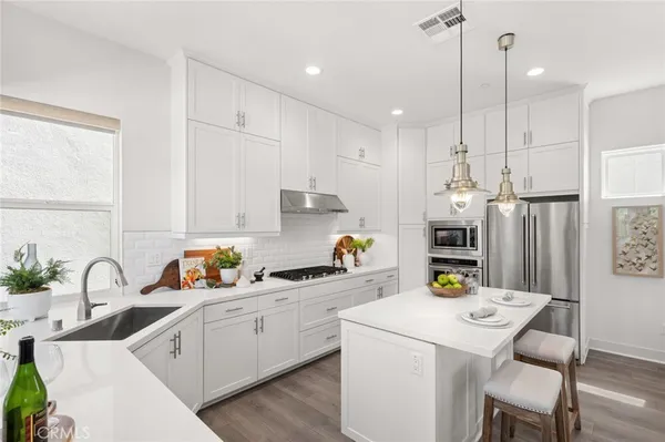 a kitchen that has a lot of cabinets a sink and appliances in it