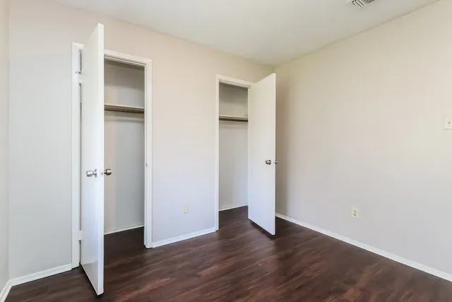 a view of an empty room with wooden floor and closet