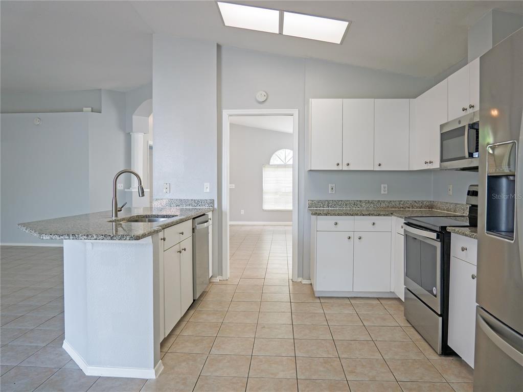 4768 Ridgemoor Circle Palm Harbor, FL 34685 - Photo 13 of 41 a kitchen with granite countertop a sink stove and cabinets