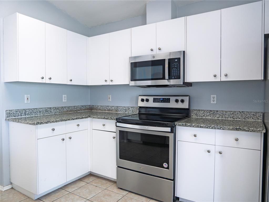 4768 Ridgemoor Circle Palm Harbor, FL 34685 - Photo 14 of 41 a kitchen with stainless steel appliances granite countertop white cabinets and a stove a oven with white countertops