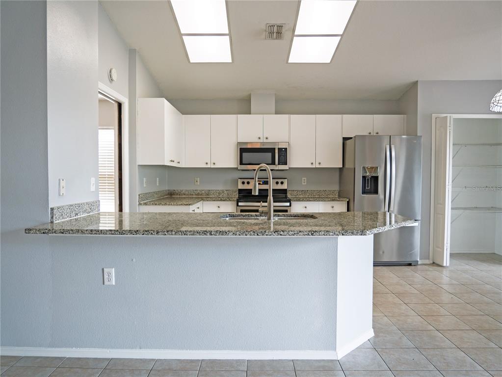 4768 Ridgemoor Circle Palm Harbor, FL 34685 - Photo 15 of 41 a kitchen with stainless steel appliances granite countertop a sink a stove a refrigerator a washer and dryer with wooden cabinets