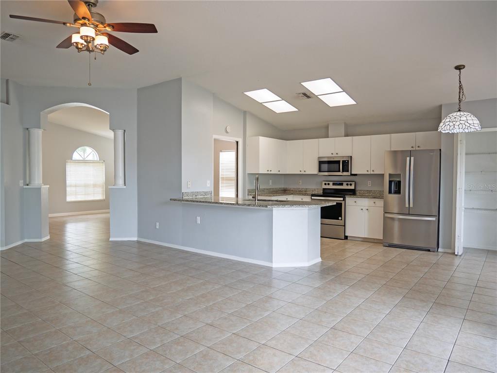 4768 Ridgemoor Circle Palm Harbor, FL 34685 - Photo 6 of 41 a kitchen with stainless steel appliances kitchen island granite countertop a refrigerator a stove a sink and white cabinets with wooden floor