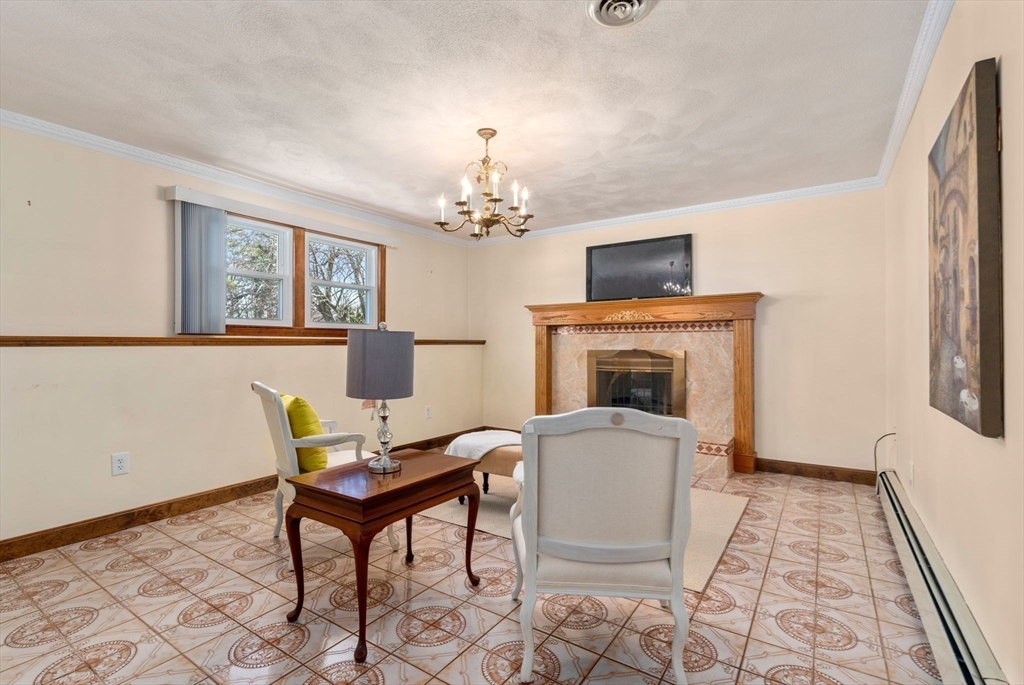 8 Sycamore Lane Saugus, MA 01906 - Photo 21 of 39 a living room with furniture a fireplace and a chandelier