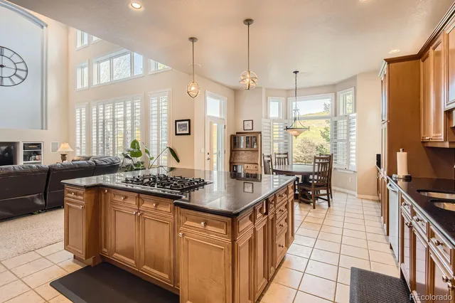 a kitchen with granite countertop a stove a sink a dining table and chairs